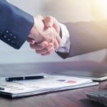 Professional handshake agreement over business charts in an office setting.